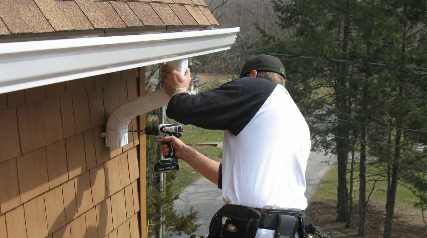 Professional contractor installing tan vinyl siding panels on a residential home exterior in Cincinnati, OH